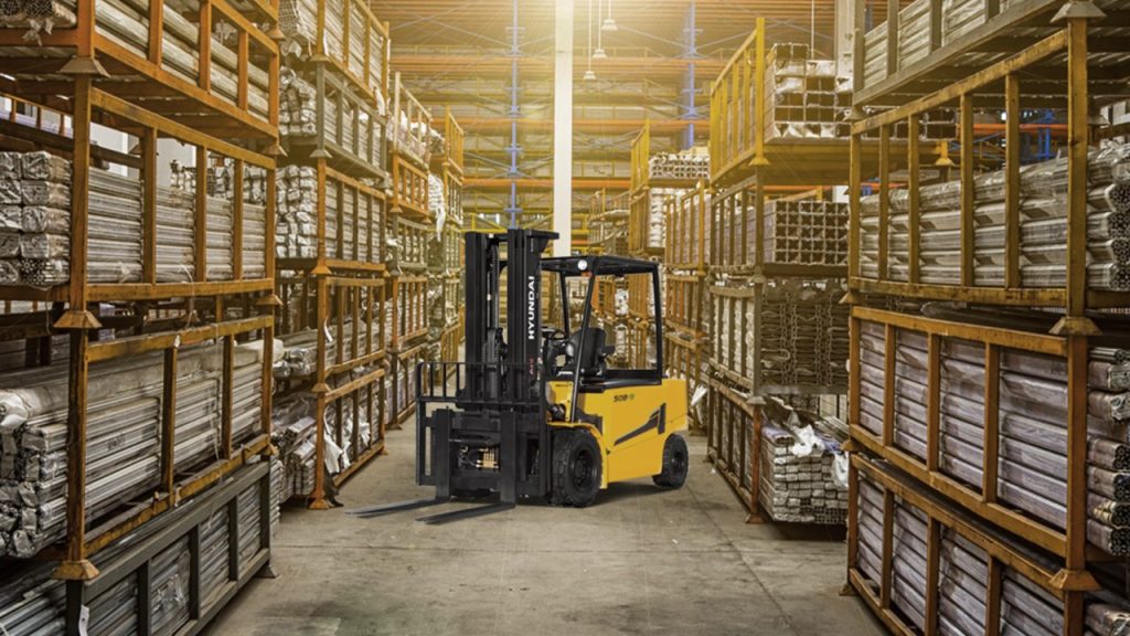 Steel pipe and tube storage yard with yellow forklift handling long steel products