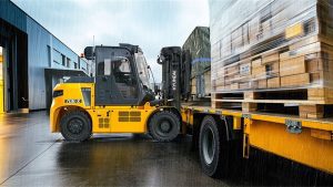 Hyundai 70B-X electric forklift loading pallets onto a truck in the rain outdoors