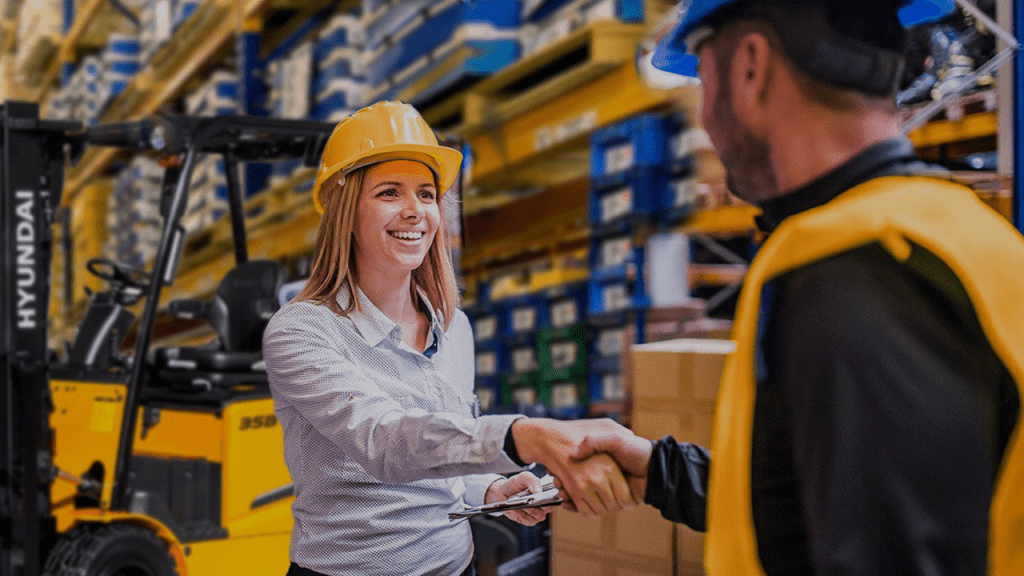 Warehouse manager in a hard hat shaking hands with a high-vis worker beside a Hyundai 35B electric forklift in a Brisbane warehouse